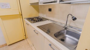 A kitchen with a stainless steel sink, a gas stove, and a cabinet with a paper on the door. - 02 Relais du Lac Village (Desenzano del Garda)