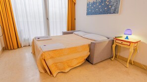Una cama doble con cabecera, una mesita de noche con lámpara y un cuadro en la pared.