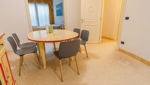 A room with a round table, six chairs, a door, and a window with curtains. - 02 Relais du Lac Village (Desenzano del Garda)