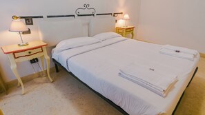 A bed with white linens, two bedside tables with lamps, and a headboard.