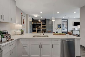 A modern kitchen with white cabinetry, a central island, and a built-in bench.