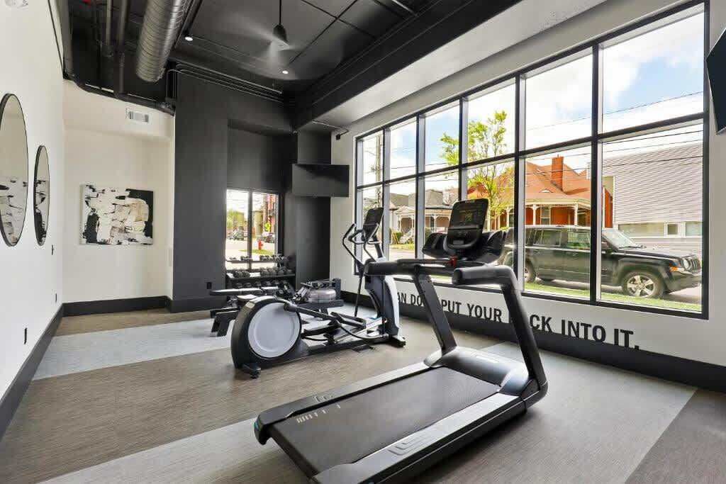 A modern gym with a treadmill, elliptical, and stationary bike.