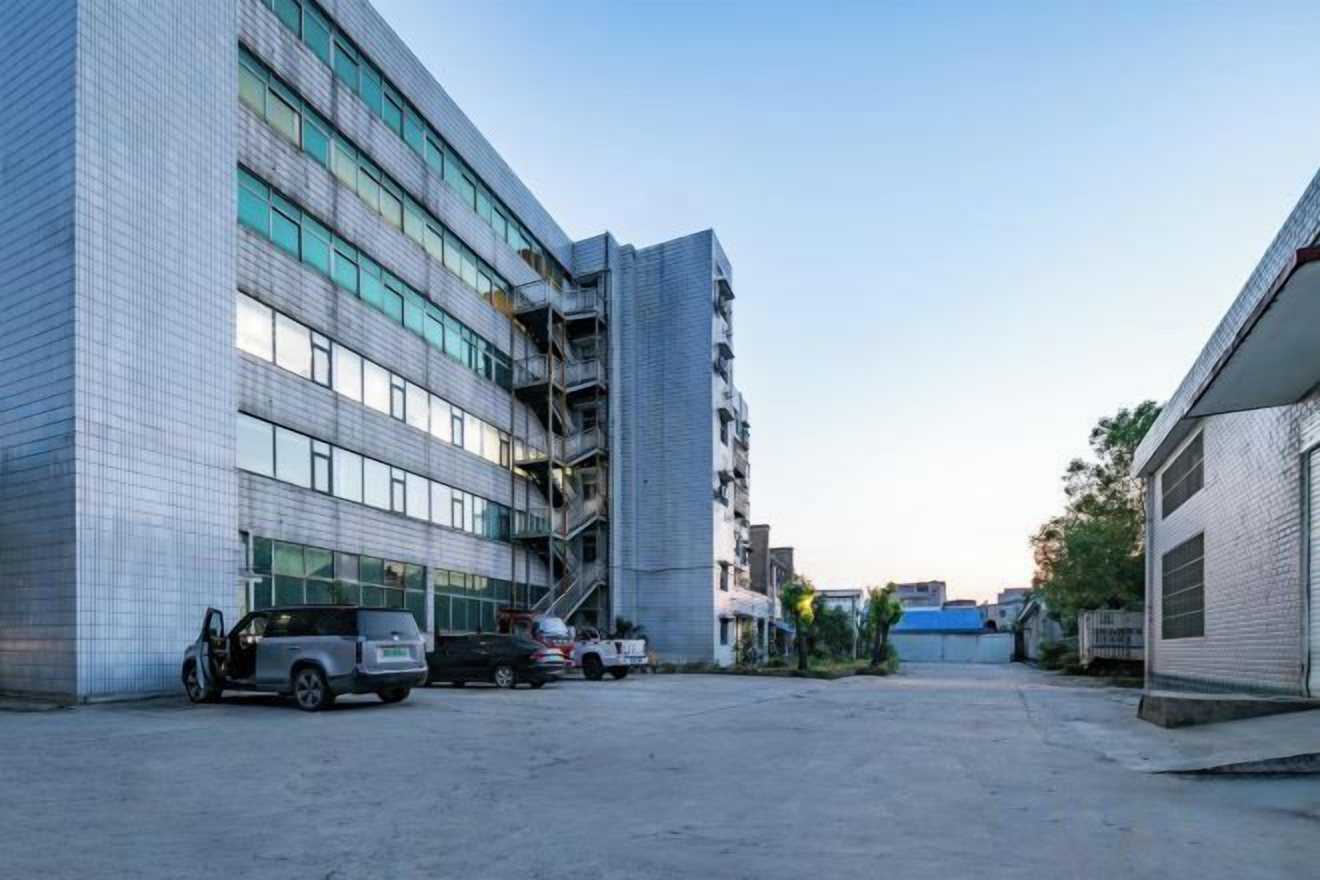 A parking lot with a building on the left and a smaller structure on the right.