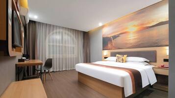 A hotel room with a bed, a desk, a chair, a TV, and a painting of a sunset.