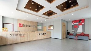 Una zona de recepció amb un taulell de fusta, un gran quadre abstracte a la paret i un disseny de sostre modern amb il·luminació empotrada.