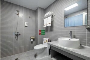 Een badkamer met een douche, toilet, wastafel en spiegel.