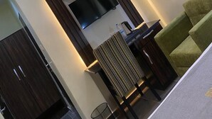A modern living room with a flat-screen TV mounted on the wall, a sofa, a coffee table, and a patterned rug. - GrandField Hotels (Ibadan)