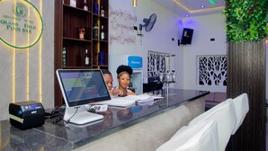 A reception area with a digital kiosk, a cash register, and a counter with a menu board. - GrandField Hotels (Ibadan)