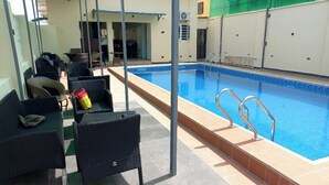 A pool area with wicker furniture and a tiled floor. - GrandField Hotels (Ibadan)