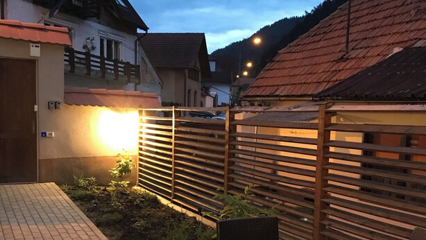 A patio area with a wooden fence, a chair, and a table. - Charming Apartment City Escape (Brasov)