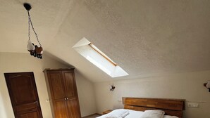 A bedroom with a skylight, wooden bed, and a nightstand. - Charming Apartment City Escape (Brasov)