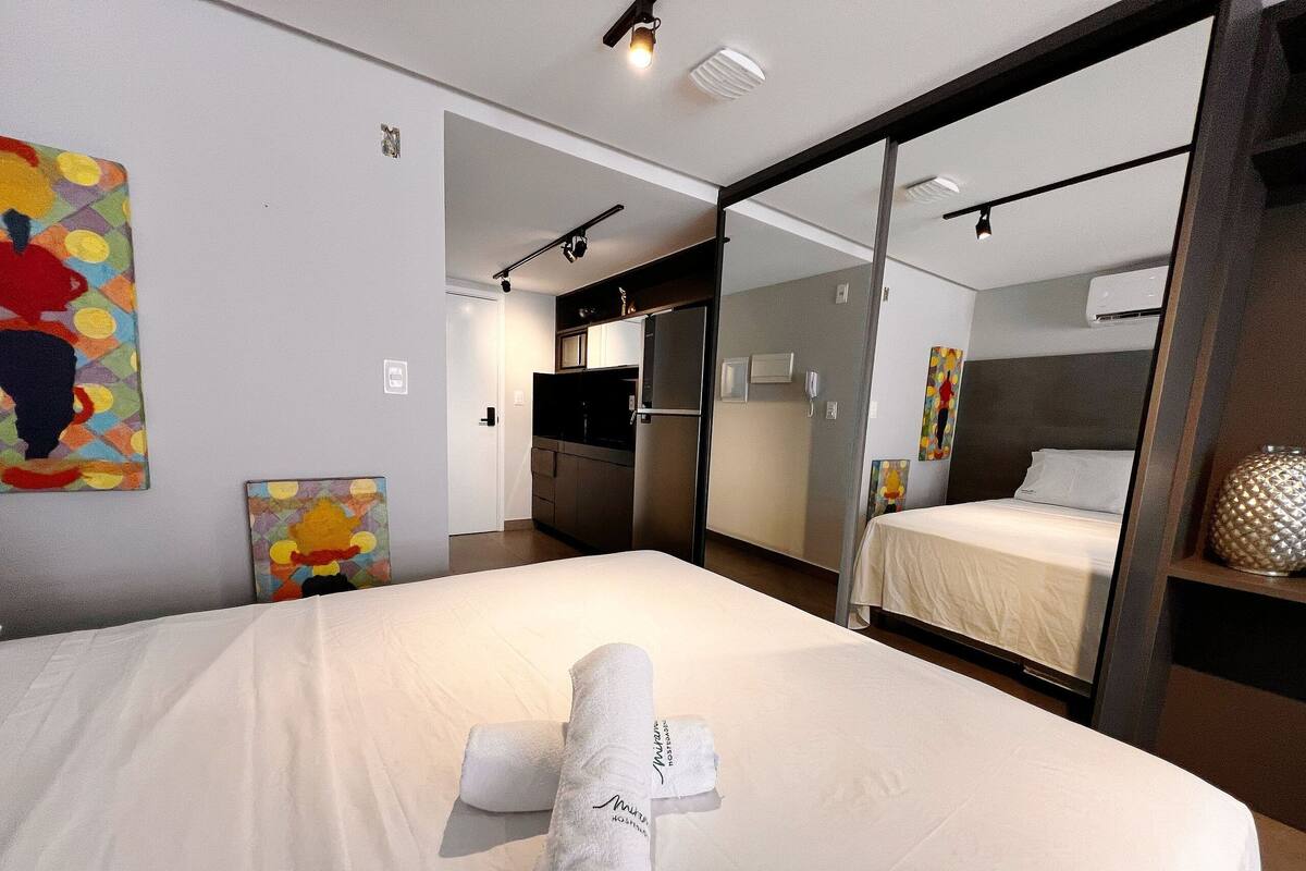 A hotel room with a large bed, a bedside table, a mirror, and a wardrobe.