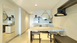 A compact hotel room with a kitchenette, a dining area with a table and chairs, a large mirror, and a hanging coat rack. - Quality by Hosppedar (João Pessoa)
