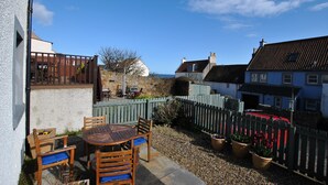 A patio with a round table and chairs, a wooden fence, and potted plants. - 2a Rose St- cosy coastal cottage Fife (Saint Monans)