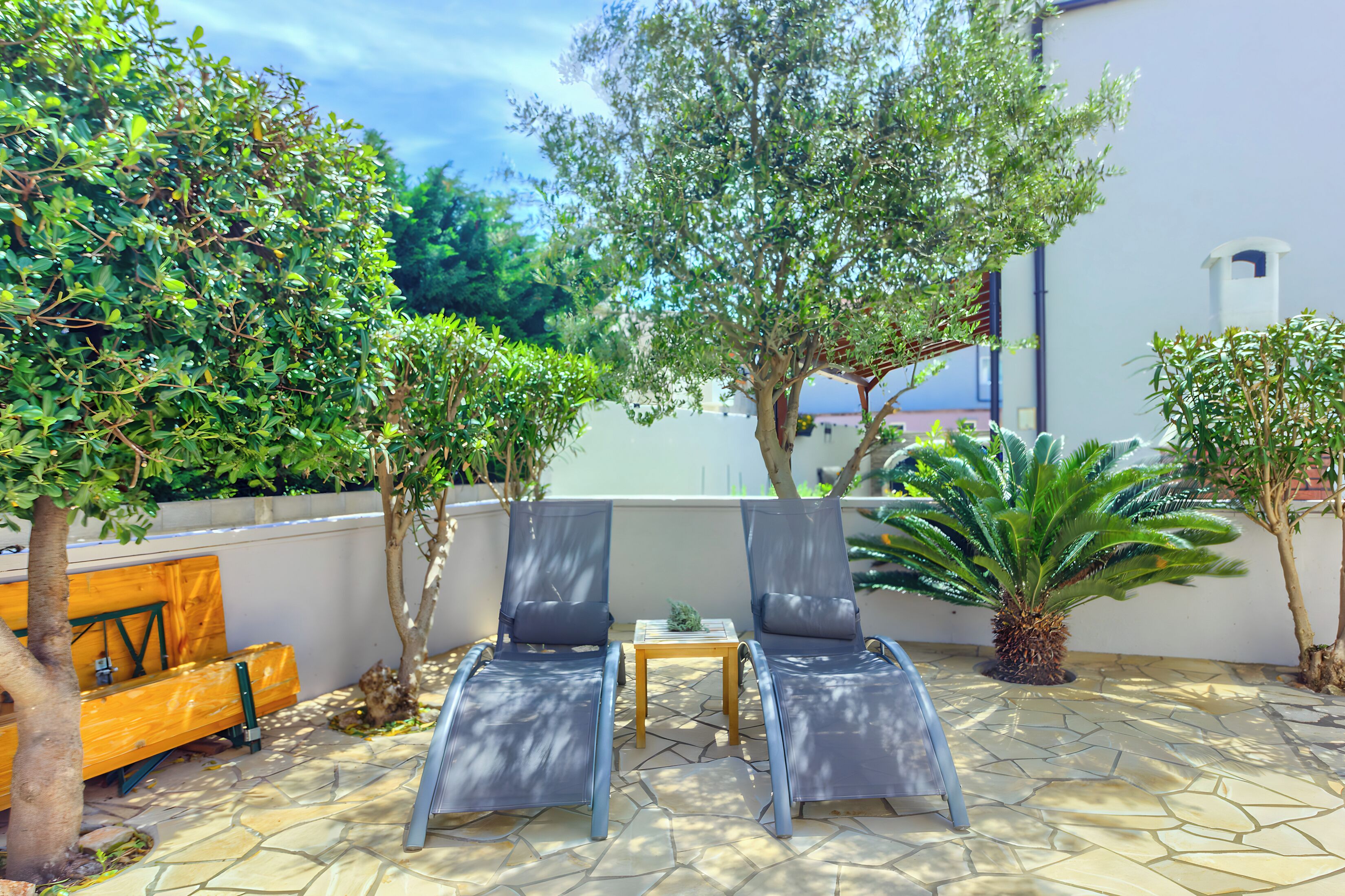 A patio with two lounge chairs, a small table, and a wooden bench.