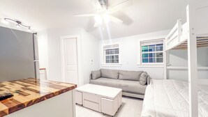 A compact room with a kitchenette, a sofa, a bed, and a ceiling fan. - On the water with kayaks and a launch, 5 mins from beach, Everything you need! (Swansboro)