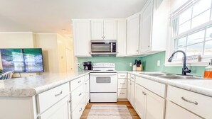A kitchen with white cabinets, a microwave, a stove, and a sink. - On the water with kayaks and a launch, 5 mins from beach, Everything you need! (Swansboro)