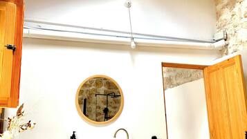 A bathroom with a skylight, wooden shelves, a sink, and a mirror.