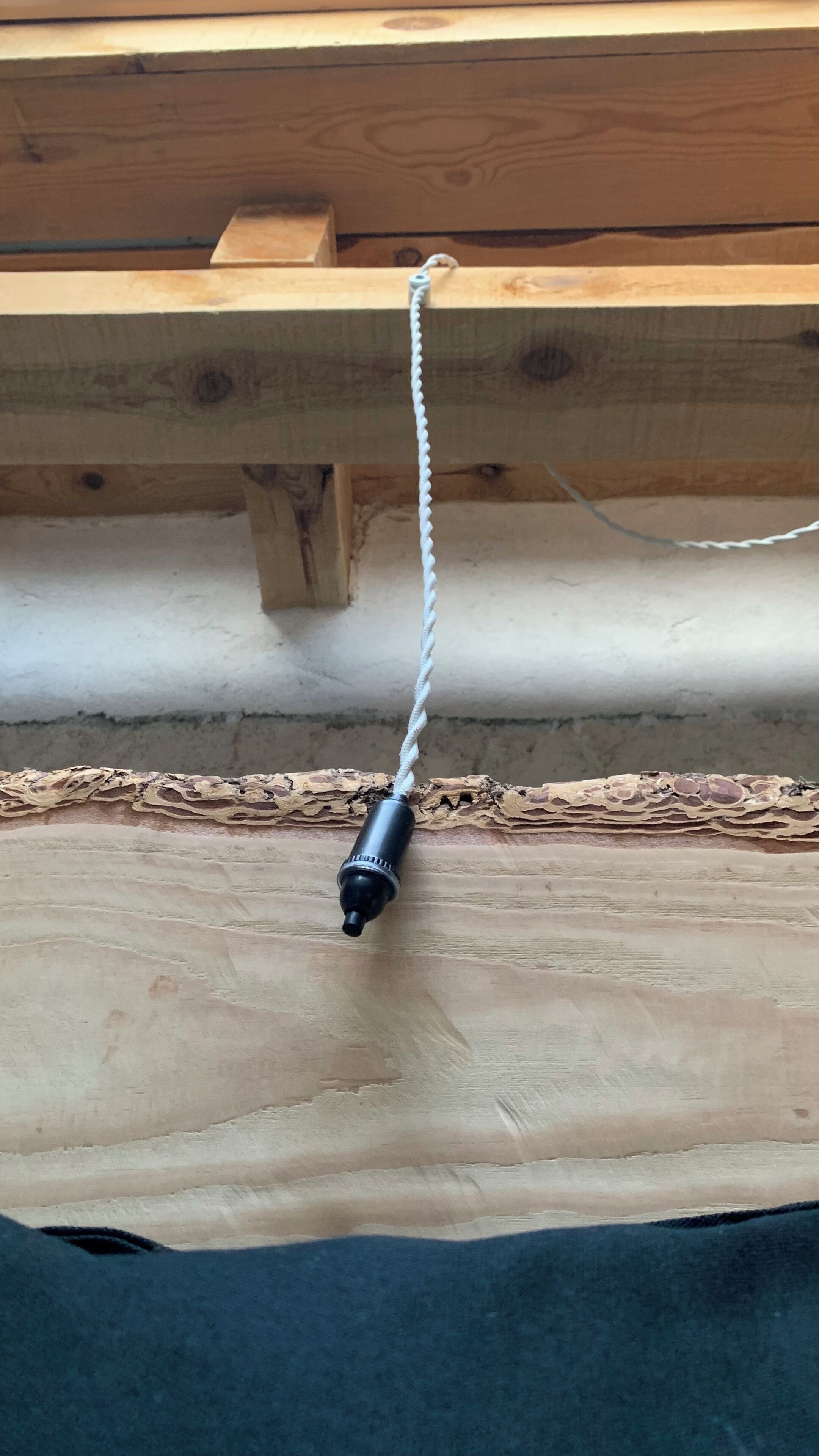 A ceiling with exposed wooden beams and a white cable running across it.