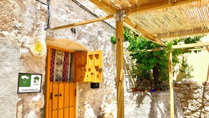 Ein rustikales Steinhaus mit einer Holztür, einem Schild mit der Aufschrift 'CASAS RURALES' und einer Holzpergola mit Kletterpflanzen.