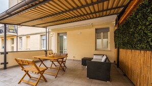 An outdoor patio with a wooden table and chairs, a sofa, and a bamboo wall. - Mutina Suite 3 (Modena)