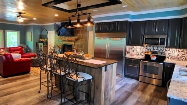 A modern kitchen with a central island, stainless steel appliances, and dark cabinetry. - 17 ft Swim Spa, hot tub, pool table, kayaks, 3 kitchens, wifi (Moneta)