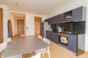 A modern kitchen with dark cabinets, a built-in oven, and a dining area with a large table and chairs. - U-GO Vistas al Mar desde Murano Centro (Cartagena)