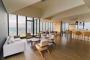 A spacious lounge area with high ceilings, large windows offering city views, and a mix of seating options including sofas and chairs. - U-GO Vistas al Mar desde Murano Centro (Cartagena)