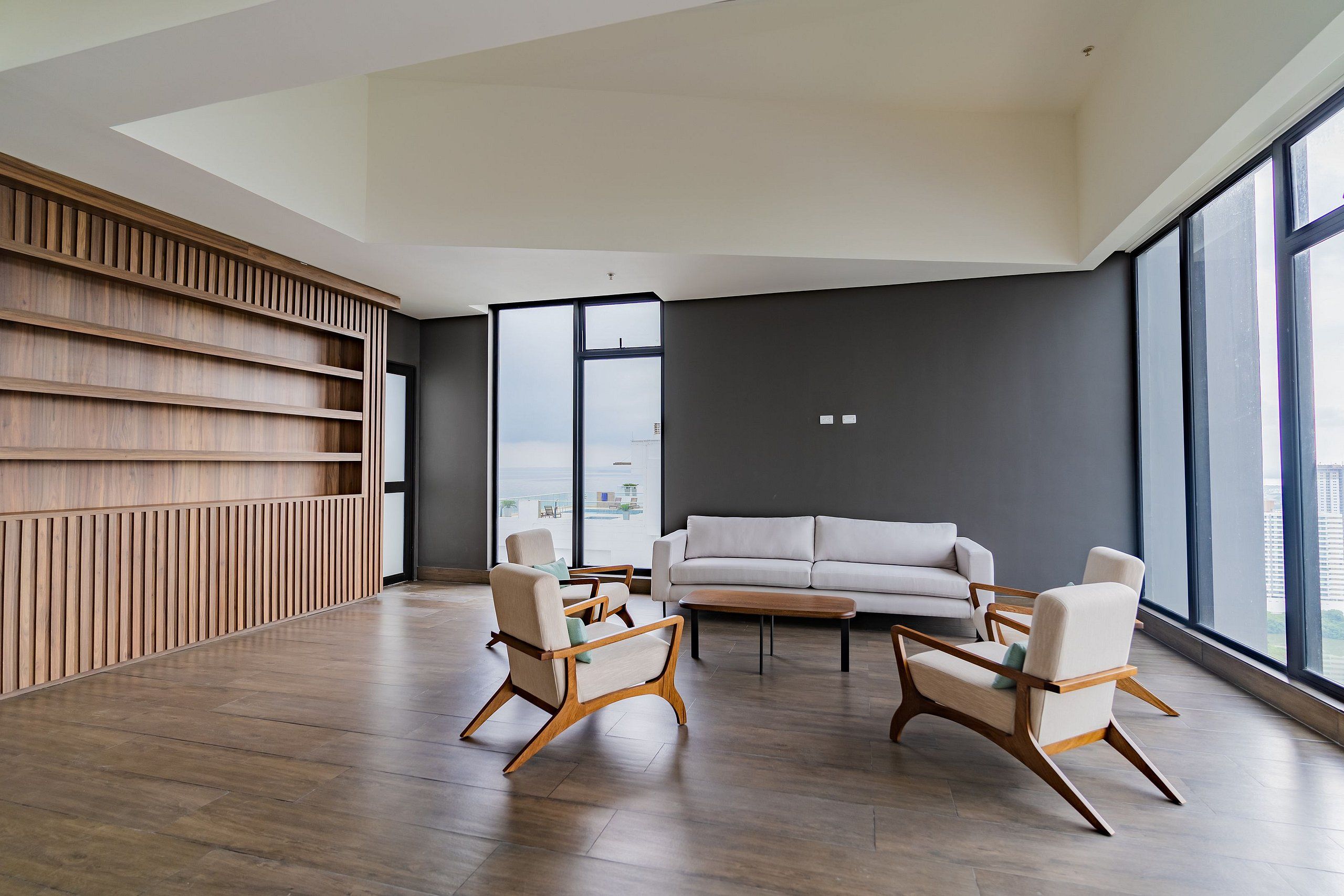 A modern living room with a large window, a sofa, and two armchairs.