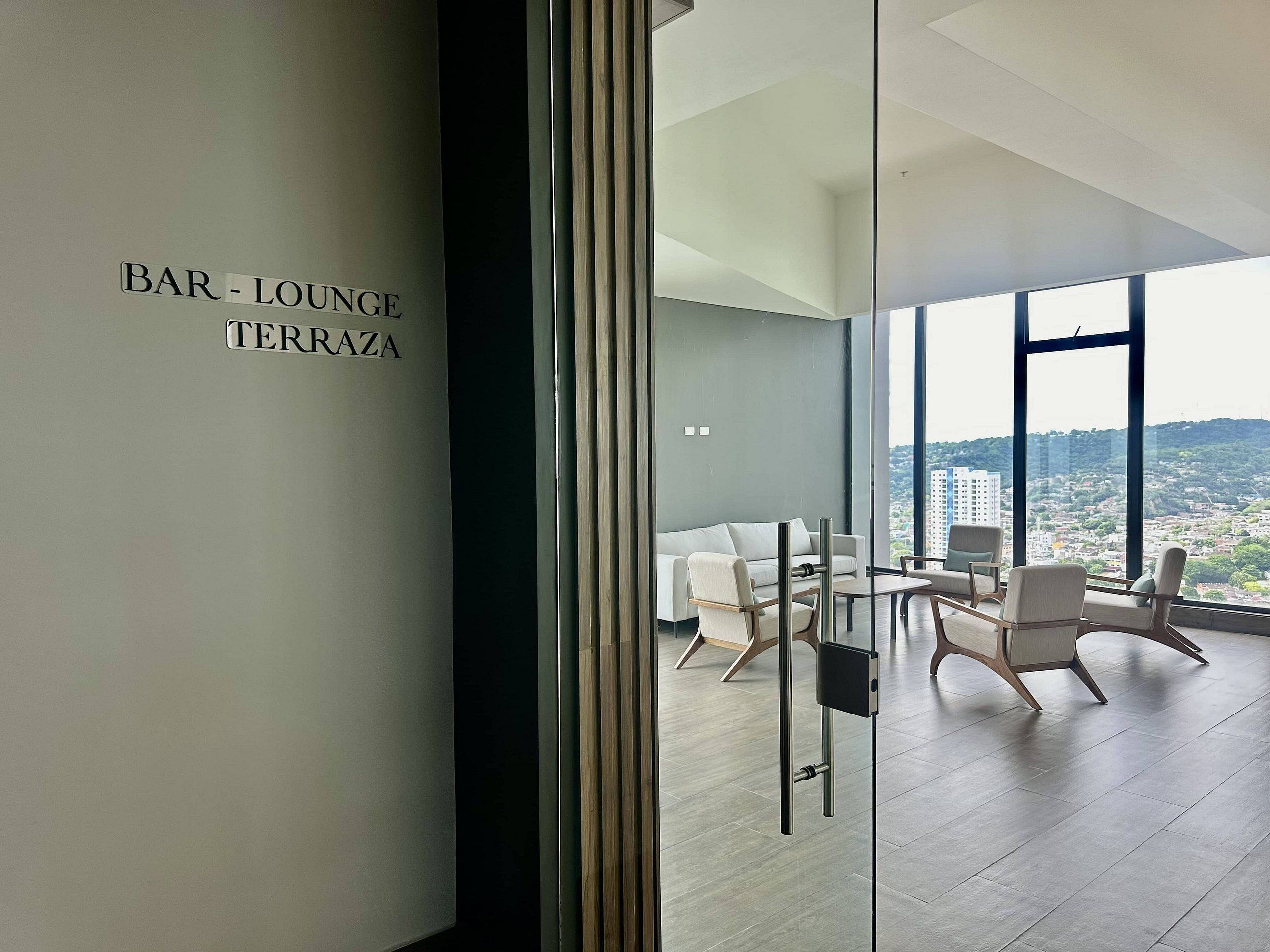 A modern lounge area with a view of a cityscape through large windows.