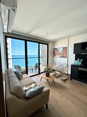 A modern living room with a sofa, chairs, a coffee table, and a view of the sea through large windows. - U-GO Vistas al Mar desde Murano Centro (Cartagena)