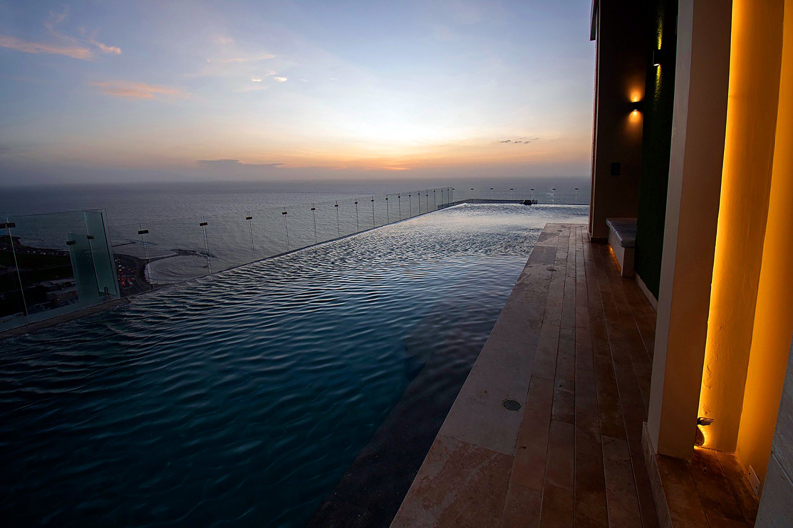 An infinity pool with a view of the ocean at sunset.