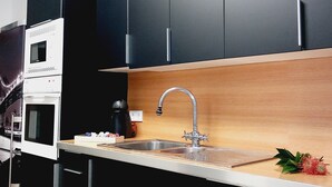 Une cuisine moderne avec des meubles de couleur sombre, un évier en acier inoxydable et un plan de travail en bois.