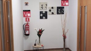 Un couloir avec un extincteur, un vase de fleurs et des œuvres d’art mural.