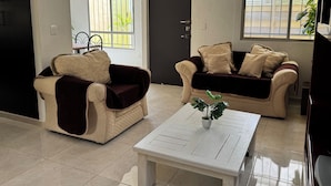 Ein Wohnzimmer mit zwei Sofas, einem Couchtisch und einer Tür.