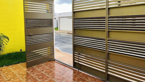 Ein moderner Gebäudeeingang mit einem Metallgitter und einer gelben Wand.