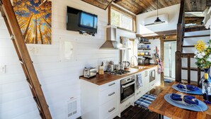 A kitchen with wooden cabinets, a stove, and a TV mounted on the wall.