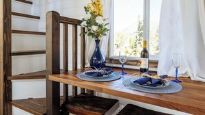 A dining table set with blue placemats, a vase with yellow flowers, a bottle of wine, and two wine glasses.