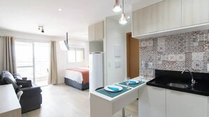 Et moderne hotelværelse med tekøkken, spiseplads og opholdsstue.