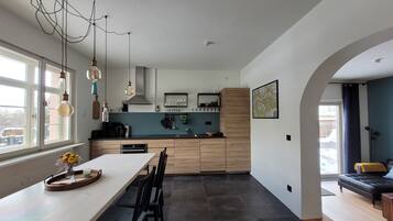 Eine moderne Küche mit Holzausstattung, einem Esstisch mit Stühlen und Pendelleuchten.