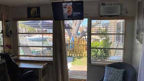 Een kamer met een bureau, stoel en een televisie aan de muur.