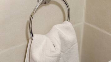 A bathroom with a white towel hanging on a chrome towel ring.