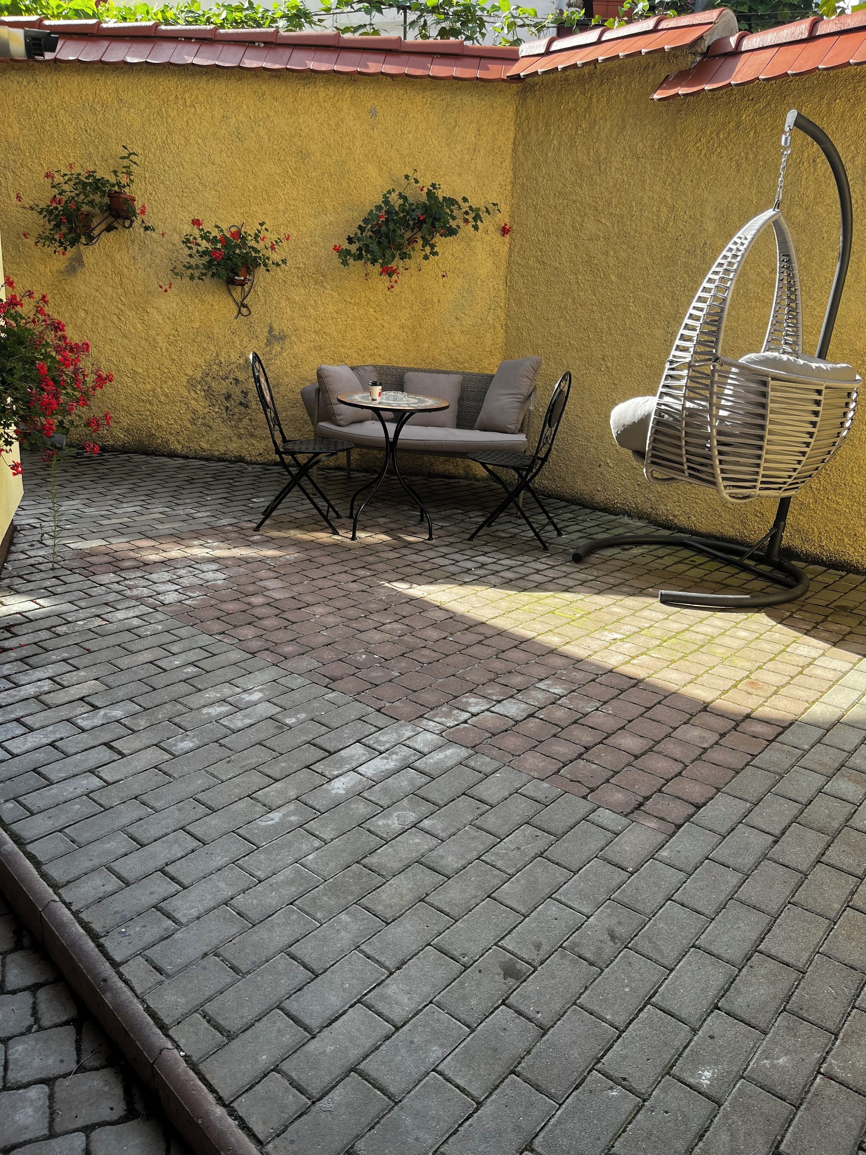 A patio with a sofa, a small round table, and a hanging chair.