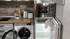 Cocina compacta con lavadora, microondas y refrigerador integrado.