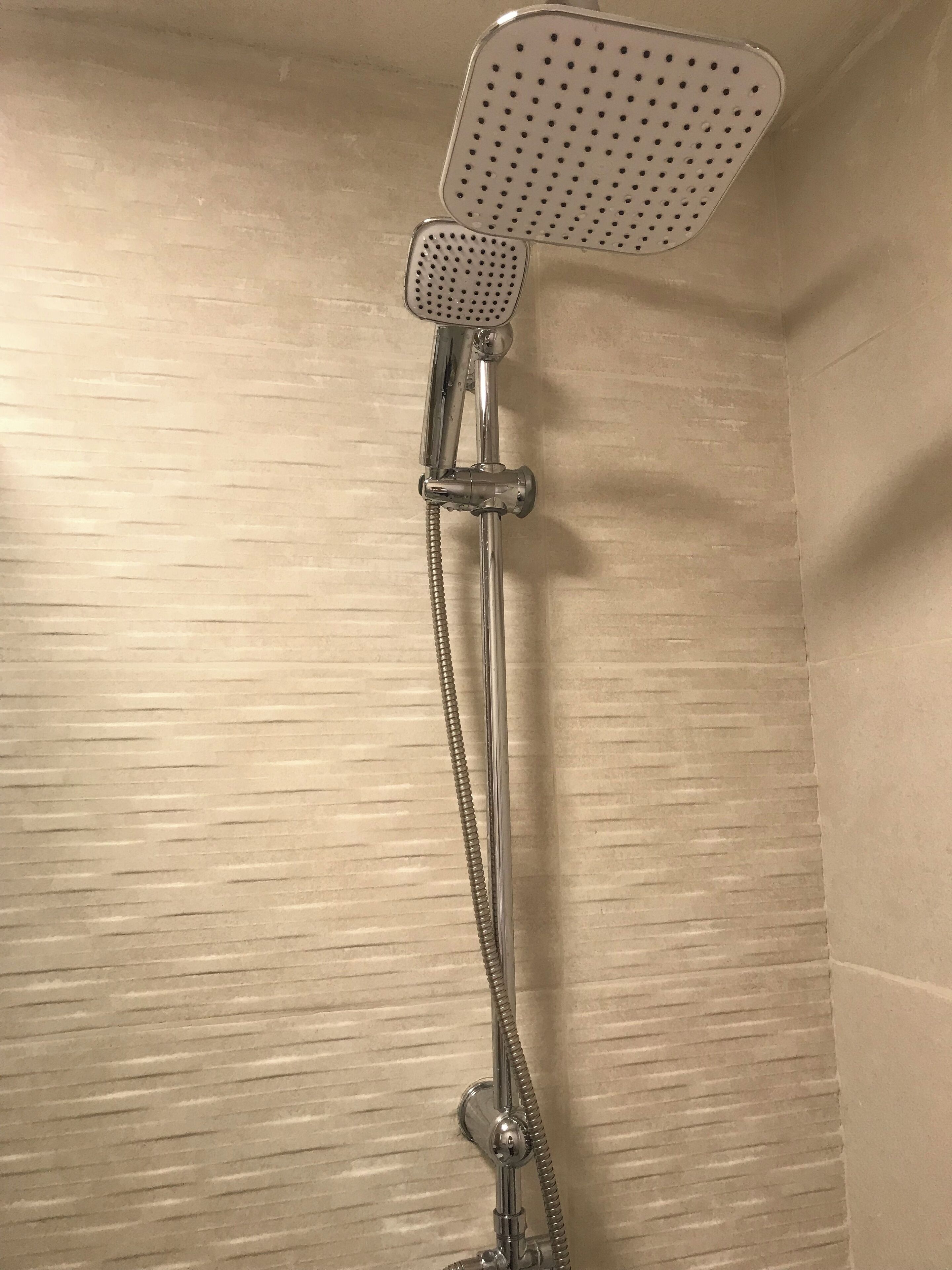 Una ducha con cabezal de ducha de mano y manguera flexible.