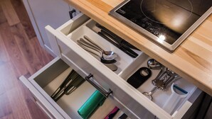 Una cocina con un lavamanos de acero inoxidable, encimera de madera y una placa de inducción empotrada.