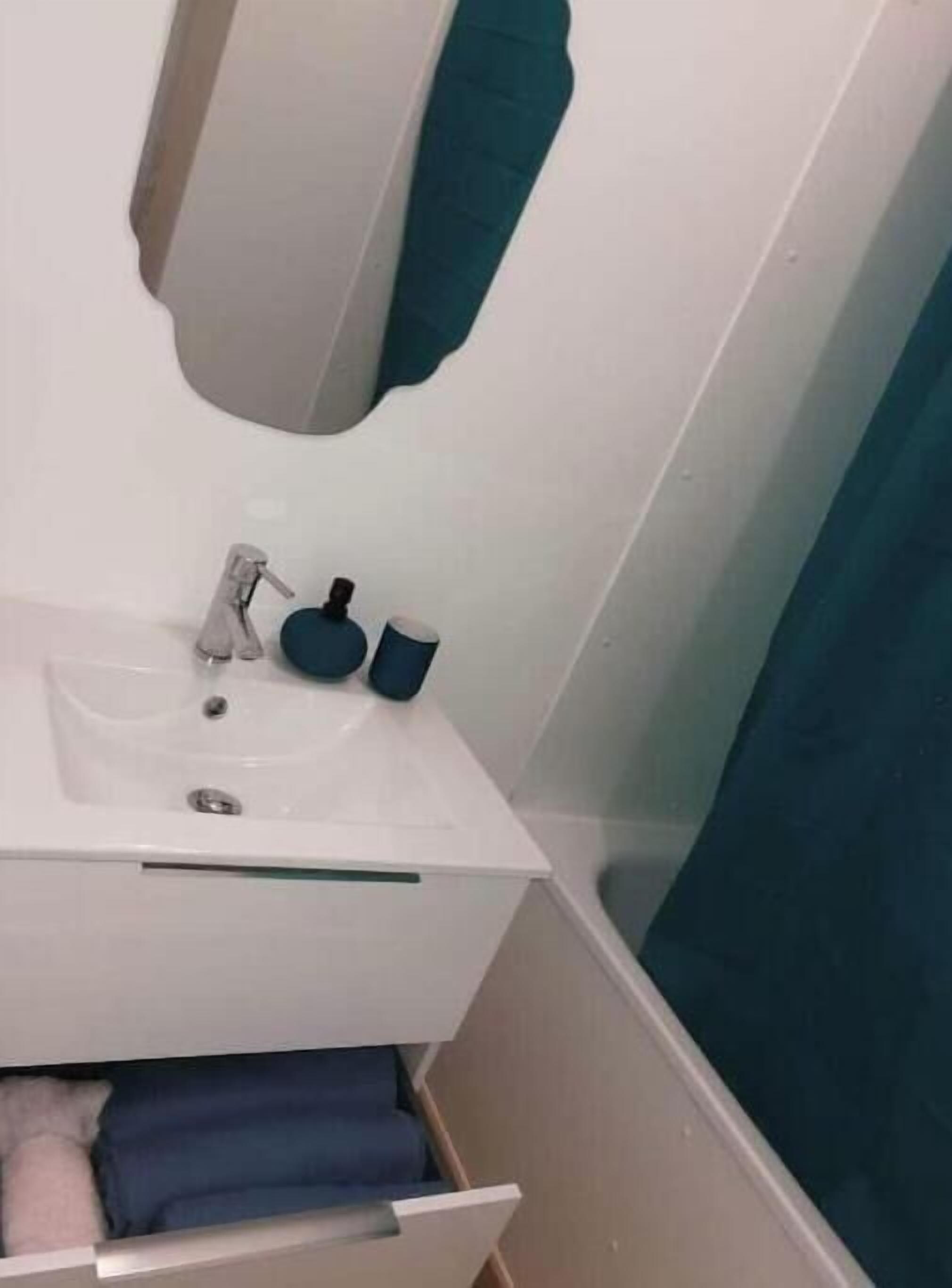 Een badkamer met een witte wastafel, een spiegel en een blauwe handdoek.