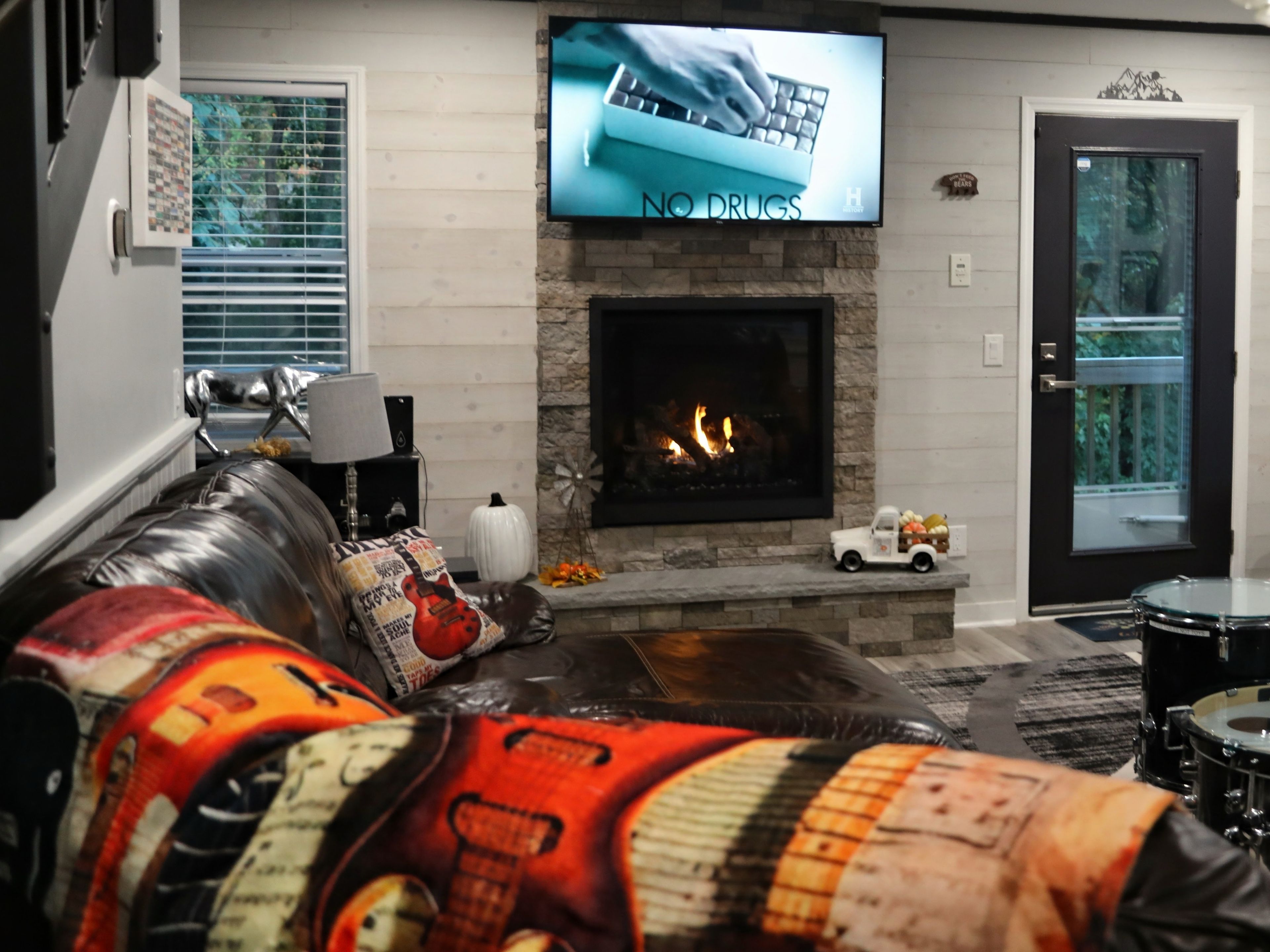 A living room with a fireplace, a television mounted above it, and a sofa with decorative pillows.
