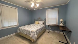 Un dormitorio con cama, mesita de noche, lámpara y ventilador de techo.