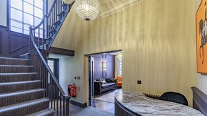A hotel lobby with a marble reception desk, a staircase, and a sofa in the background. - The Seven (Chester)